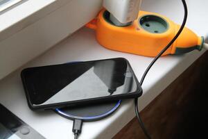 KYIV, UKRAINE - February 21, 2024 Charging an Apple smartphone, wired or wireless photo