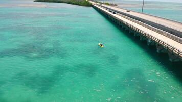 A tourist swims across the bay in a yellow kayak near the bridge. Kayaking in St. Petersburg Florida video