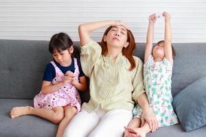 Asian single mom Headache raising two mischievous little children. The three of them sat on the sofa in the house. Family concept. Modern parenting, single mother, how to raise happy children. photo
