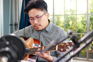 Asian musician artist Sit and play guitar in the studio. Music concept. online music lessons photo