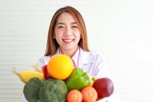 hermosa asiático nutricionista participación un bandeja de frutas y vegetales ella dio Consejo y preparar nutritivo comida comer limpio, sano alimento. salud cuidado concepto foto