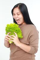 Fat Asian woman eating lettuce to lose weight. Concept of eating healthy, clean, safe. White background. photo