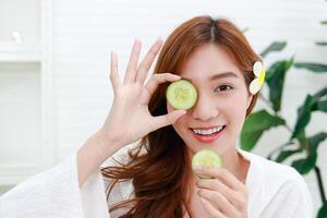 hermosa asiático niña haciendo spa a hogar cara máscara con Pepino hacer tu cara claro sin acné, reducir oleaginosidad en el rostro, nutrir el piel a ser suave y suave. belleza concepto foto