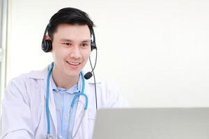 asiático masculino médico sonriente hermosamente Proporcionar tratamiento servicios para pacientes con en línea conversaciones vía el Internet en ordenador portátil ordenadores. en línea médico concepto. Copiar espacio foto