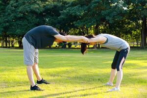 asiático Pareja hacer ejercicio juntos en el parque en el Mañana ellos son fuerte y saludable. al aire libre ejercicio concepto, salud cuidado, calentar extensión foto