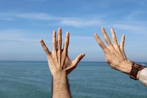 Hand doing,showing number gesture symbol nine on blue summer sky nature background. Gesturing number 9. Number nine in sign language. Ninth. photo