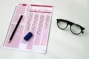 Optical reader, pencil, glasses, and eraser on it. Exam, idea conspet. Future Anxiety. Uncertainty. Multiple choice exam.Adults taking the exam. photo