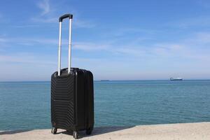 A suitcase is standing on a beach with a sunset in the background. Travel, holiday and vacation consept. Summer time. photo