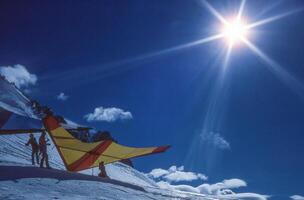 a man standing on a snow covered slope with a kite photo