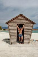 joven muscular hombre hacer ejercicio en el playa, joven muscular hombre haciendo culturismo ejercicios en el playa, atlético joven hombre en el playa foto