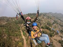parapente en el montañas, el dos personas en el parte superior de el montaña, el paracaidistas son volador con un paracaídas foto