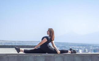 joven niña haciendo ejercicio en el ciudad, mujer haciendo yoga ejercicio, persona haciendo extensión, mujer relajante en el ciudad, bonito niña haciendo aptitud ejercicio foto