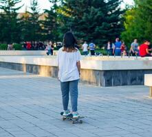 joven niña jugando en el patio de juegos, niña con patineta, joven niña en patineta en el parque foto