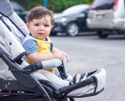 bebé chico en paseante en el jardín foto