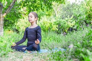 pretty girl doing yoga exercises, little girl doing yoga exercises in the garden photo