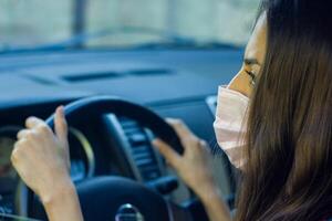 young woman in car, young woman with protective mask driving car photo