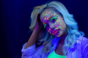 retrato de un mujer con pintado rostro, mujer con uv maquillaje en estudio, retrato de un mujer en carnaval mascarilla, el mujer es decorado en un ultravioleta polvo foto