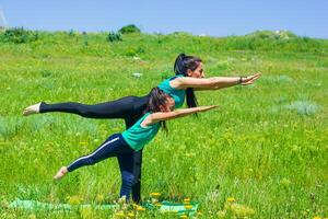 young mother and daughter doing yoga exercises, young woman  doing yoga exercises in the park photo