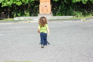 contento pequeño chico jugando en el parque, largo pelo chico en el parque foto