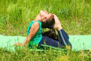 pequeño niña en el campo, pequeño niña haciendo yoga ejercicios en el parque foto