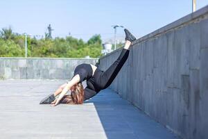 joven niña haciendo ejercicio en el ciudad, mujer haciendo yoga ejercicio, persona haciendo extensión, mujer relajante en el ciudad, bonito niña haciendo aptitud ejercicio foto