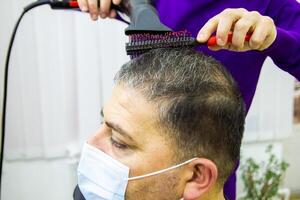 hairdresser is cutting clients hair in barber shop photo