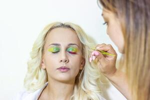 pretty young woman applying make up in beauty salon photo