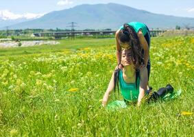 young mother and daughter doing yoga exercises, young woman  doing yoga exercises in the park photo