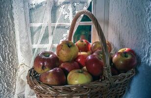 un cesta lleno con manzanas sentado en un ventana umbral foto