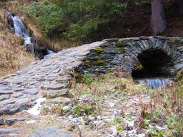 a stone bridge over a stream photo