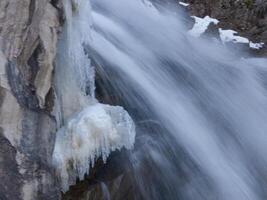 un persona es en pie en un rock siguiente a un cascada foto