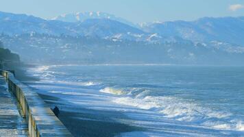 Meer Surfen und Kieselsteine im das Morgen Sonnenlicht. Berge und Bucht im das Hintergrund. echt Zeit. video