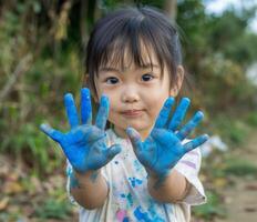 ai generado un joven niña demostración su manos pintado en azul, mundo Arte día ilustración foto