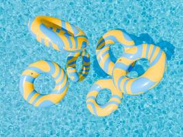 Blue and Yellow Striped Swim Rings Flying over a Swimming Pool photo