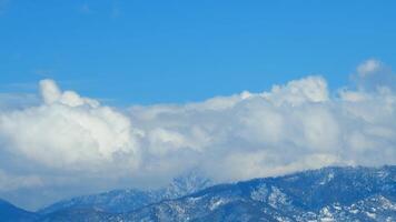 nuvens oposto direção corrente dentro frente do neve coberto montanha. montanha tops dentro nuvens. espaço de tempo. video