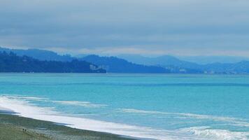 Seashore On A Cloudy Day With Rocks. Strong Waves On The Shore. Mountains In The Distance. Still. video