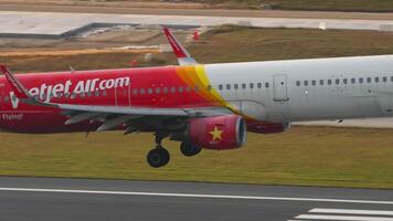 PHUKET, THAILAND - FEBRUARY 13, 2023. Airbus A321, HS-VKH of VietJet Air landing and touching with smoke at Phuket airport, side view. Cinematic shot of flight arriving video