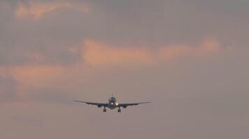 Jet plane with unrecognizable livery approaching landing in pink sunset video