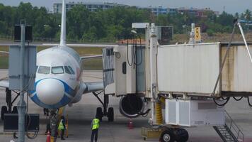 Phuket, Thailand - - Februar 28, 2023. Airbus a320 von Bangkok Luft beim das Terminal von Phuket Flughafen. teleskopisch Gangway angedockt zu ein Flugzeug. Vorbereitung von Flugzeug Vor Flug. video