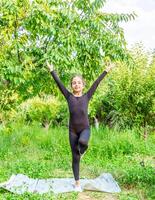 pretty girl doing yoga exercises, little girl doing yoga exercises in the garden photo