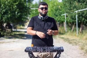 DJ con auriculares y mezclador en el parque, el DJ a trabajo foto