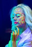 retrato de un mujer con pintado rostro, mujer con uv maquillaje en estudio, retrato de un mujer en carnaval mascarilla, el mujer es decorado en un ultravioleta polvo foto