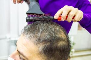 hairdresser is cutting clients hair in barber shop photo