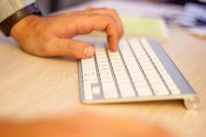 hands typing on a laptop in office photo