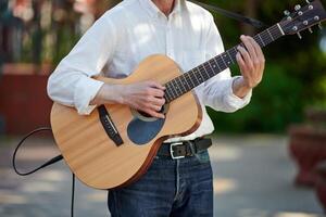 Man playing electro acoustic guitar at outdoor event, free musical performance of street musician photo