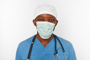 Black surgeon doctor man in blue coat white cap and surgeon mask with stethoscope white background photo