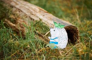 Little hedgehog paper craft with ship on needles on green wood background, cute children craft photo