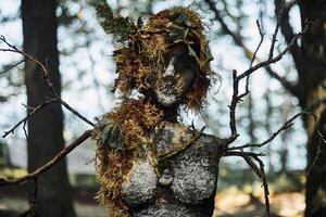 Creepy witch statue art object on forest background made of mud plaster and dry grass gloomy statue photo