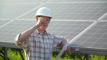 Engineer in a white helmet is at the solar power station. Alternative energy concept video