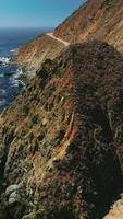 Craggy rugged coastline of California. Dark blue Pacific Ocean with algae accumulation on surface. Top view. Vertical video